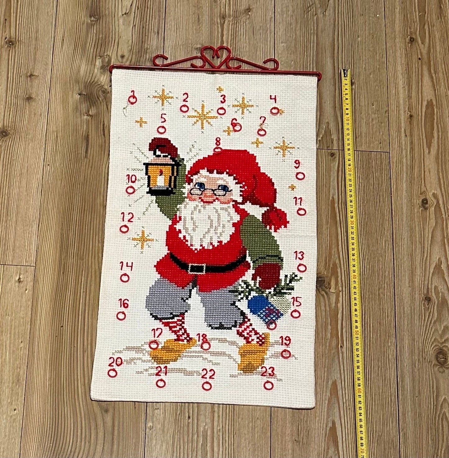 Flott håndbrodert julekalender med Julenisse og rødt beslag i metall (35 x 61cm)