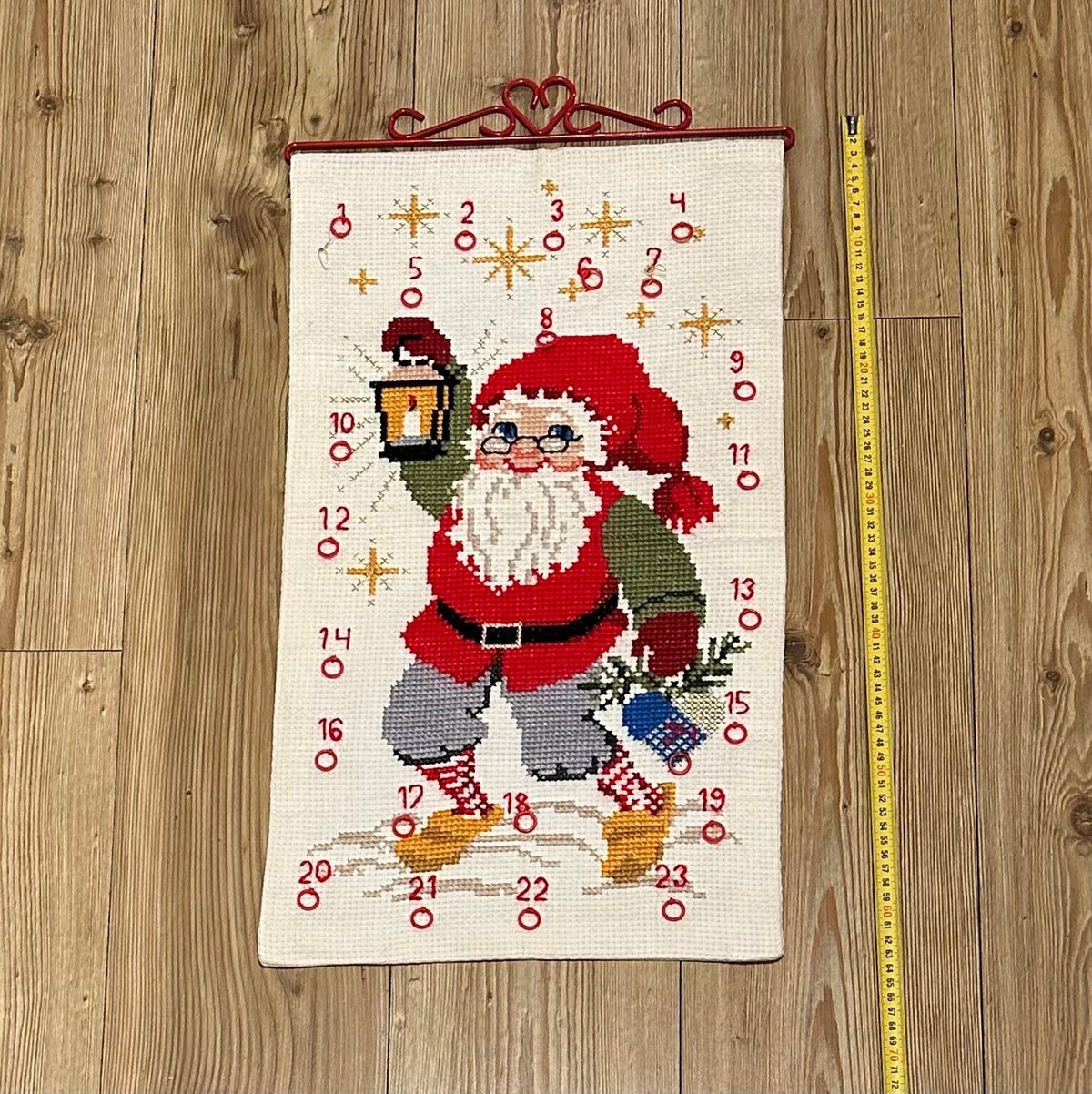 Flott håndbrodert julekalender med Julenisse og rødt beslag i metall (35 x 61cm)