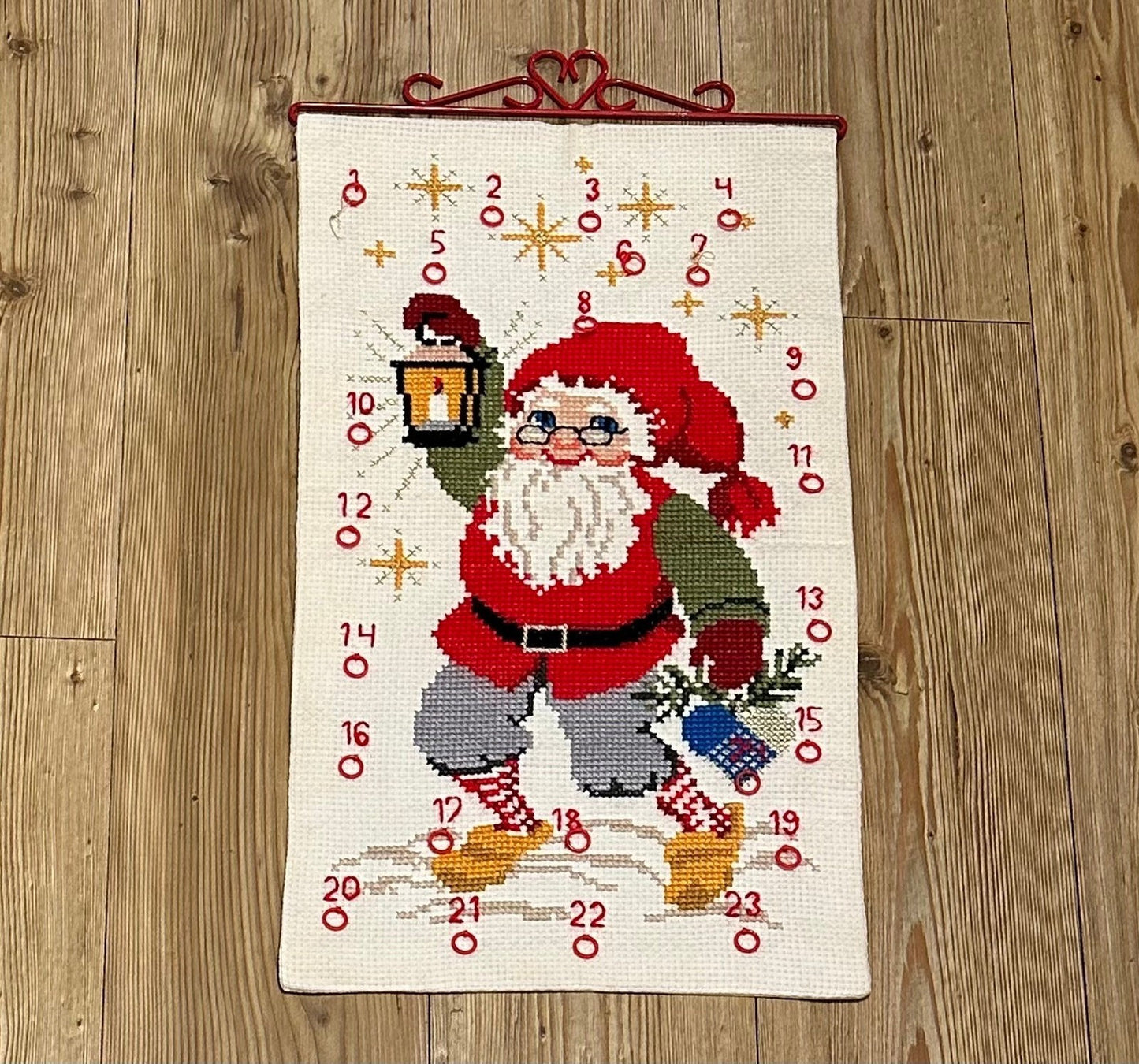 Flott håndbrodert julekalender med Julenisse og rødt beslag i metall (35 x 61cm)