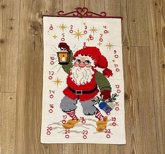 Flott håndbrodert julekalender med Julenisse og rødt beslag i metall (35 x 61cm)