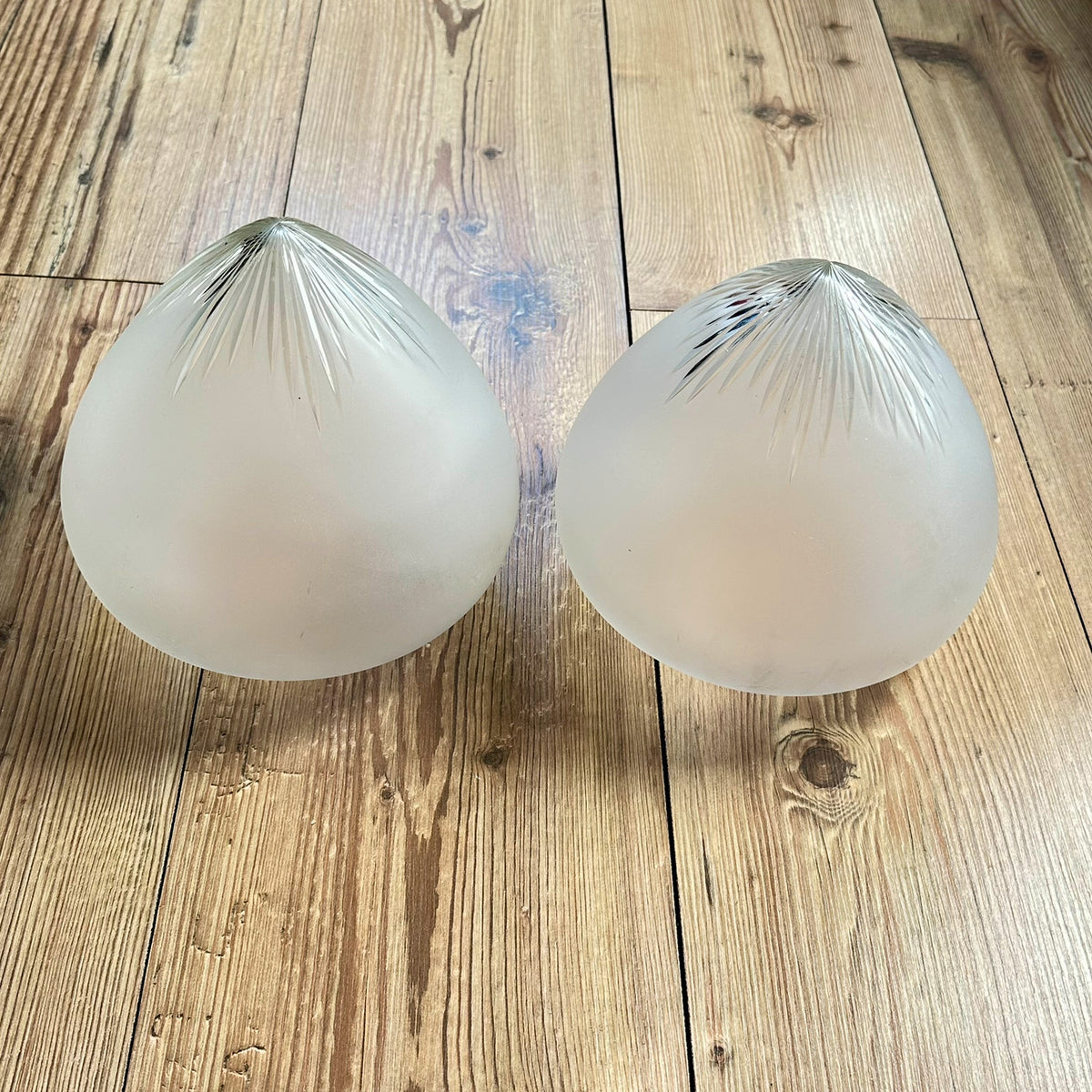 Gamle ovale lampeskjermer i semi-transparent glass med en kuttet stjerne øverst.